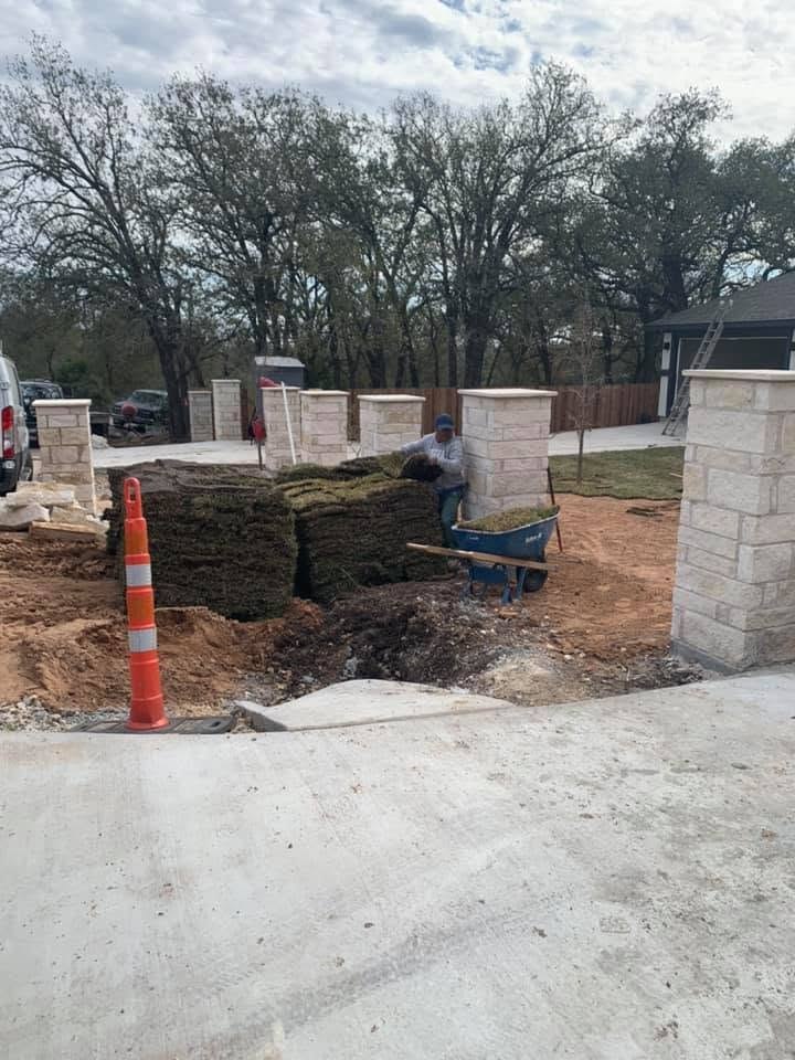 Crew installing sod around the stone pillars at house 347